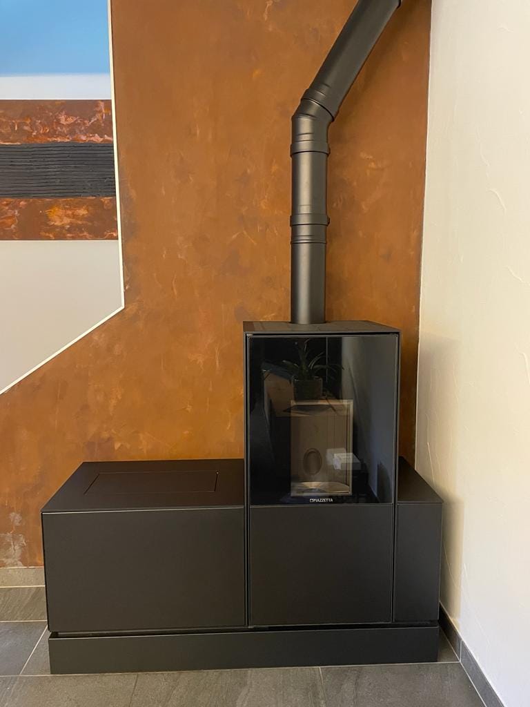 Poêle noir moderne contre mur orange.