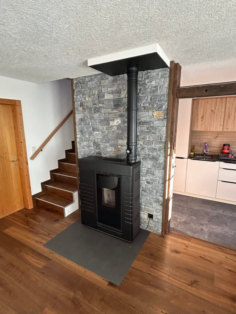 Poêle noir devant mur en pierre.