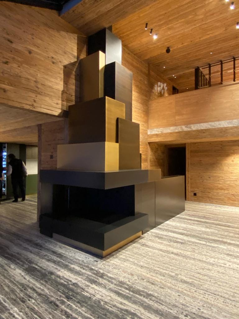 Grande cheminée moderne en métal dans salon en bois.